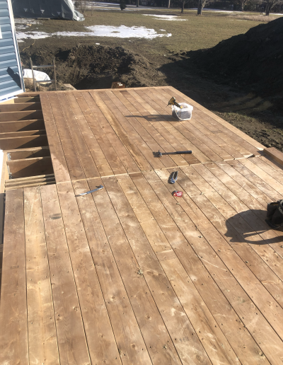 the first few planks laid of a custom Sienna wood deck in smiths falls