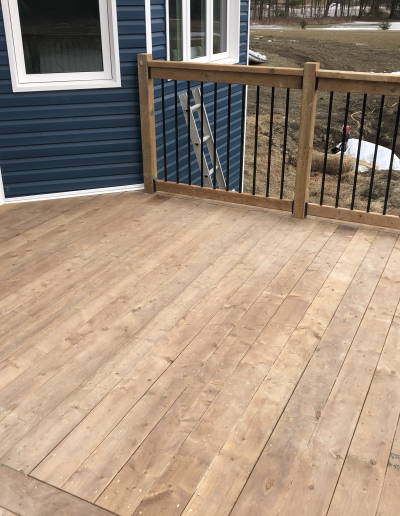 brand new wooden deck backing onto a blue house with white trim